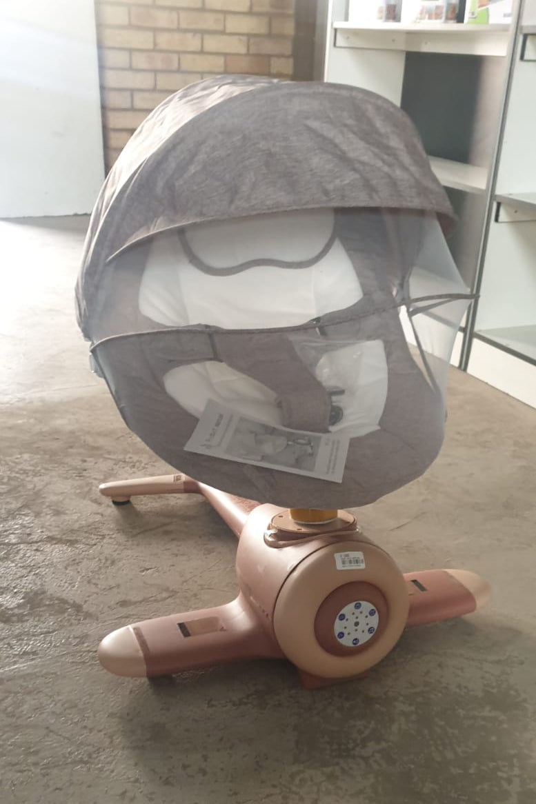 Baby swing chair with canopy on a white rug in a room with striped wallpaper